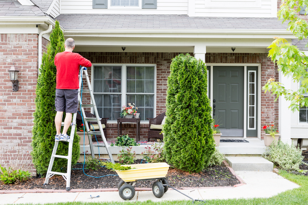 man trimming bushes thinking about cost of yard maintenance